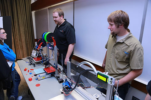 Two male students with a 3-D printer.