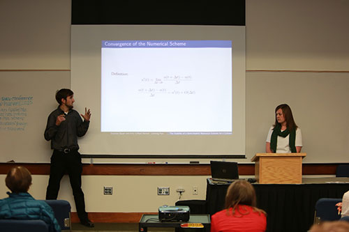 A male and female presenter presenting information from their slides.