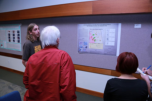 Student in a Star Wars T-shirt explaining content from a poster to interested individuals.