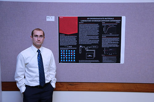 Man standing in front of a poster depicting the Hydrogen Diffusion Experiment