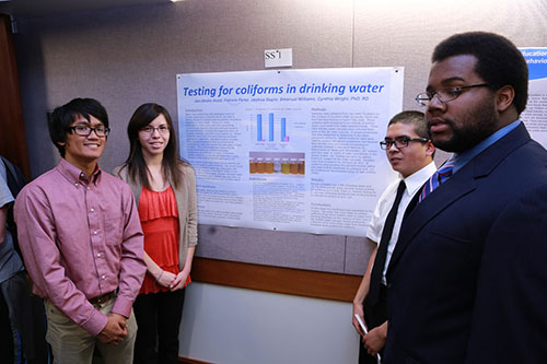 Perez, Sagisi, Williams, and Acob standing with their research poster.