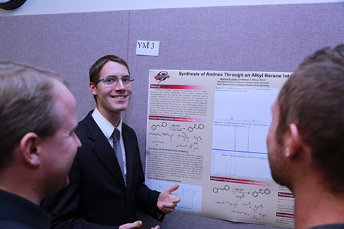 Matthew Prater presenting his research to two interested individuals.