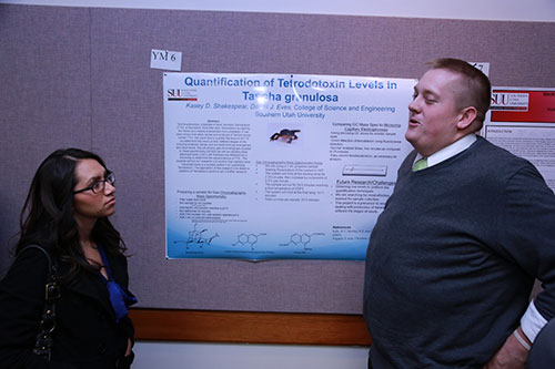 A man speaking to a female about information found on his poster.