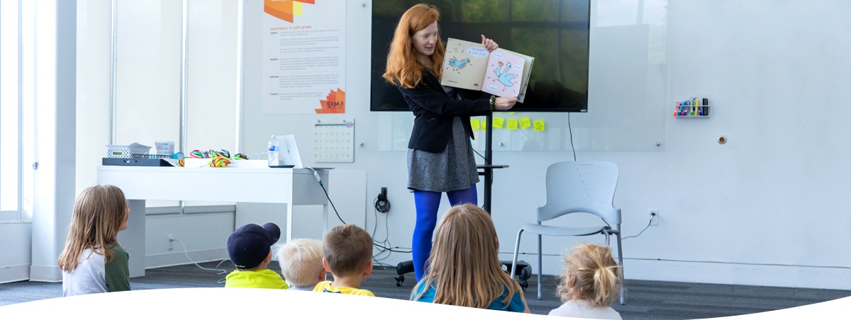 volunteer holding a book in front of kids