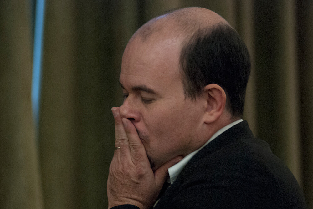 Balding man with his fingers pressed against his mouth 10