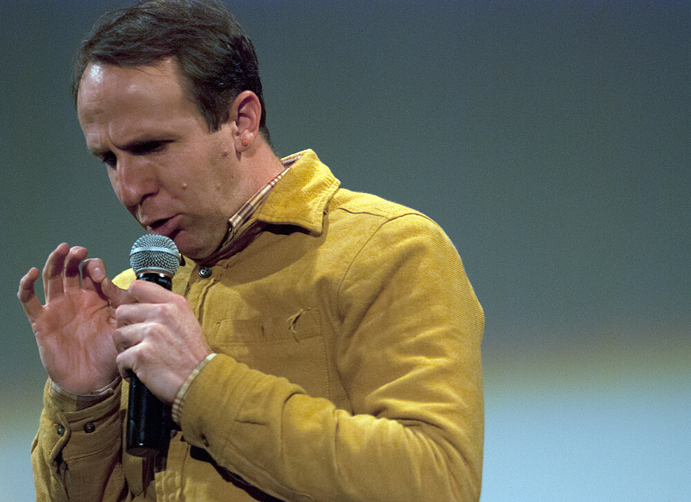 Close-up of a man speaking down into a microphone. 4