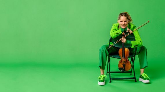 Photo of violinist Aubree Oliverson. She poses on a chair with a green background.