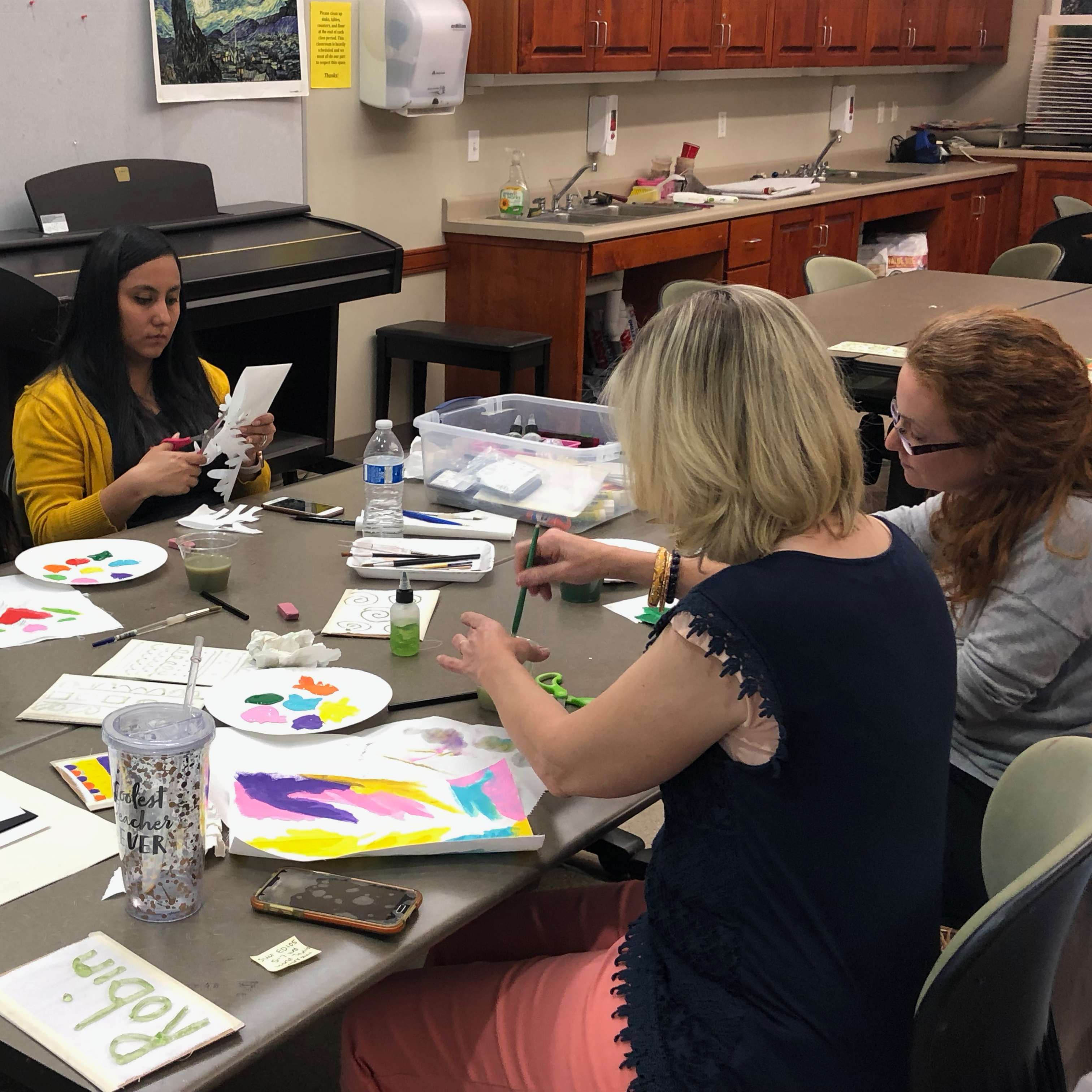Teachers painting on canvas with purple blues and yellows