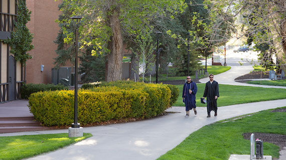 Students in cap and gown walking across campus