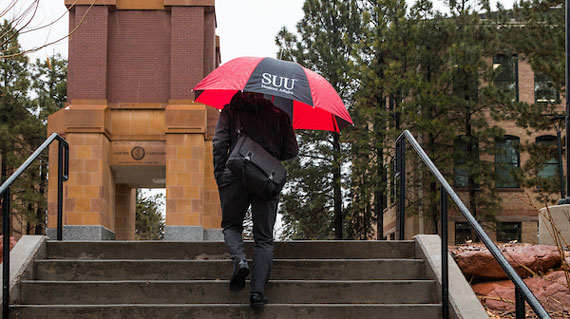 Student walking on campus with an umbrella