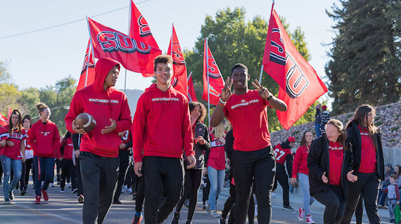 students in a parade wearing suu shirts and holding suu flags
