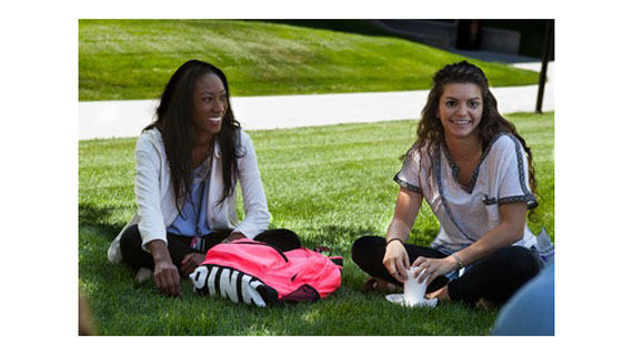 Two students sitting on grass on campus
