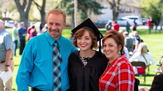 Student in cap and cown with parents