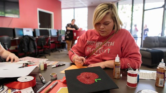Student decorating her graduation cap with an apple sticker