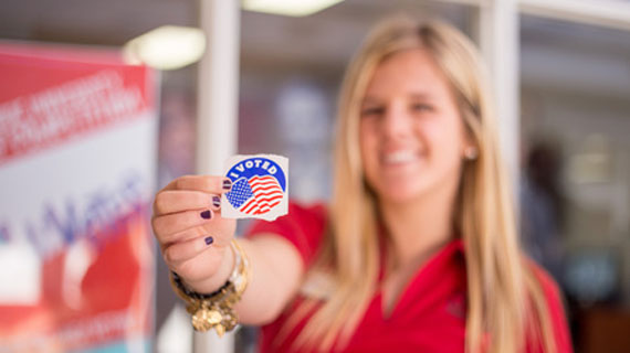 Student holding an "I Voted" sticker