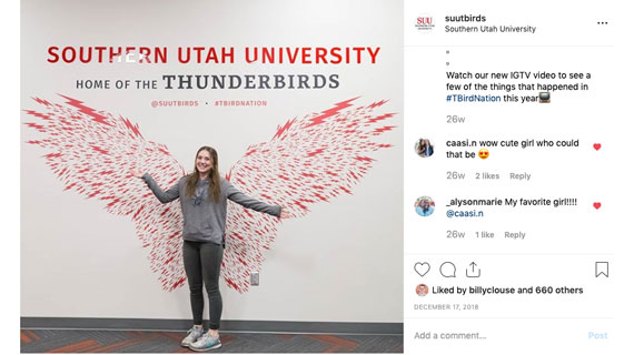 student posing in front of tbird wings on wall