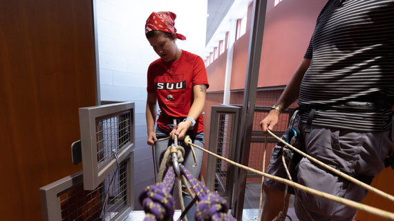 SUU Student rappelling down the climbing wall facilities
