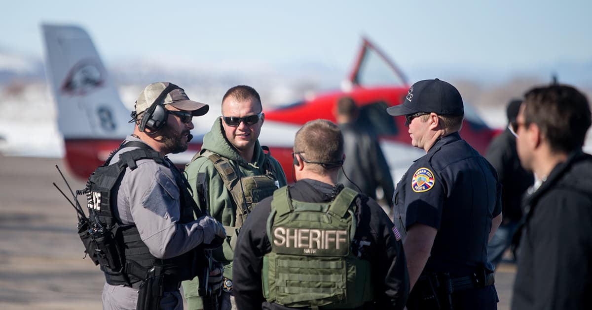 SWAT members talk in a group in front of an SUU airplane.