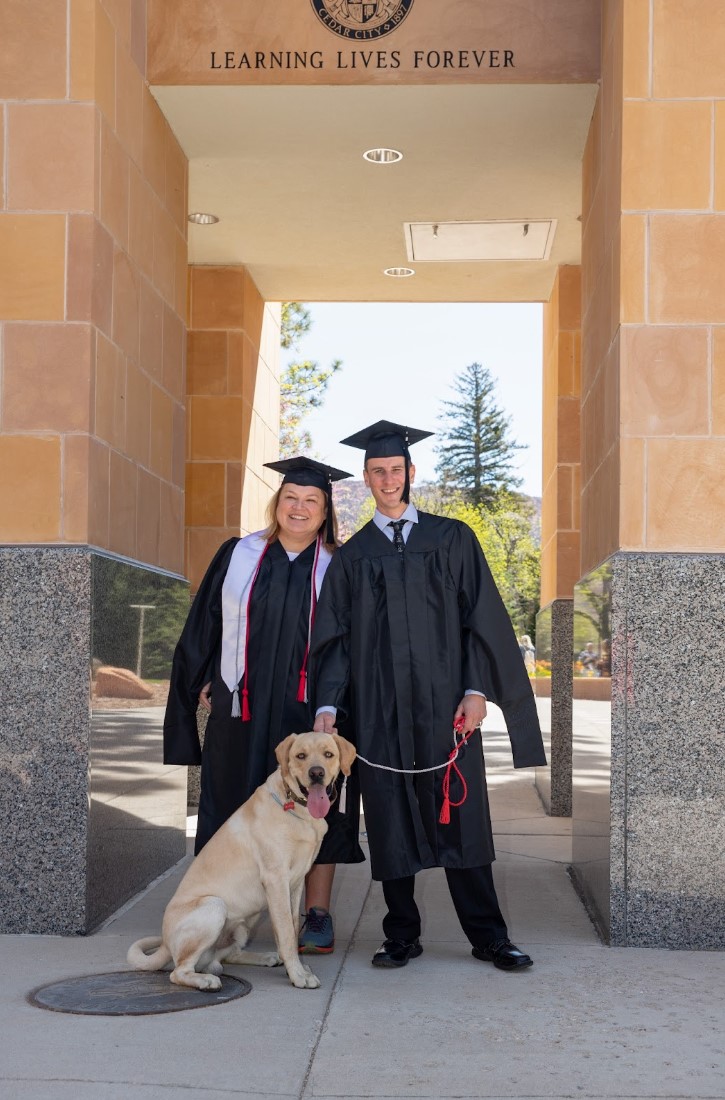 Suu's first MIS graduates with the Animal Services emphasis pose with a dog on graduation day.