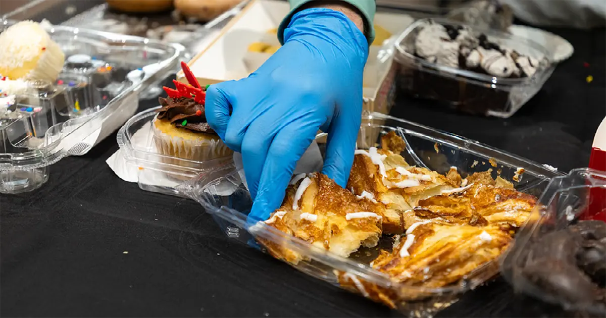Close up of a gloved hand serving a dessert.