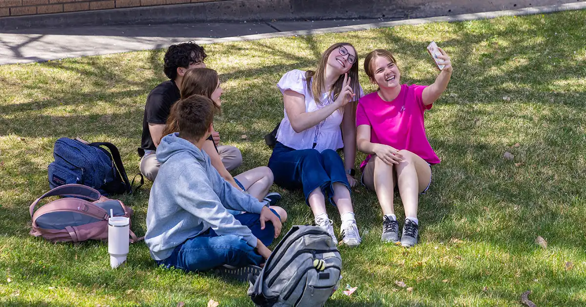 A group of five college students smile and pose for a selfie.