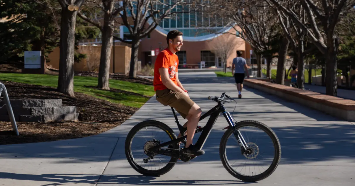Person on bicycle in front of SUU Library on campus