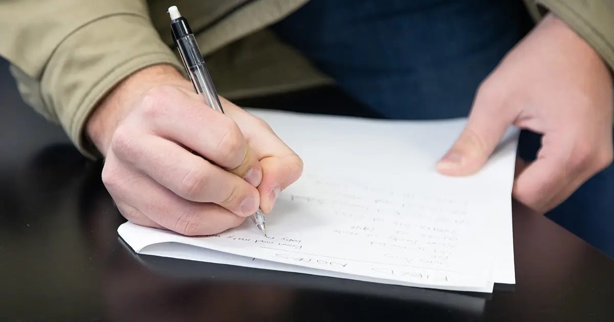 A close-up image of a person writing on a piece of paper