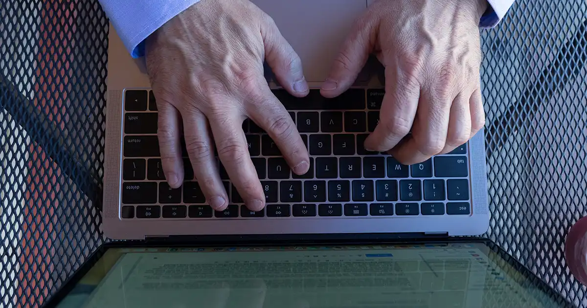 Overhead shot of hands typing on laptop keyboard. 