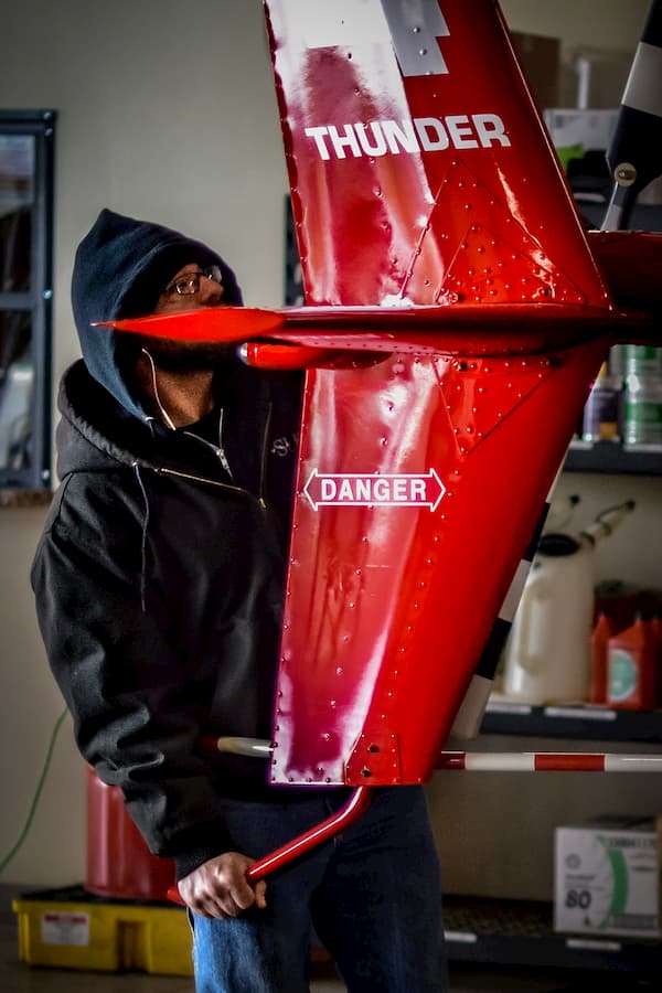 A&P mechanic student holding the tail of an R44 helicopter