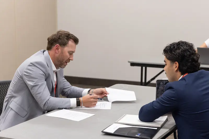 A man presenting to another man across a table 3 7