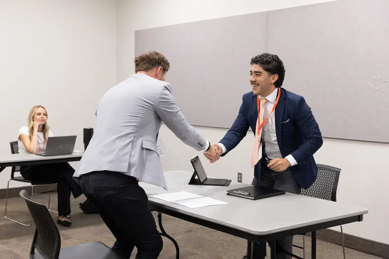 Two men shaking hands across a table 8