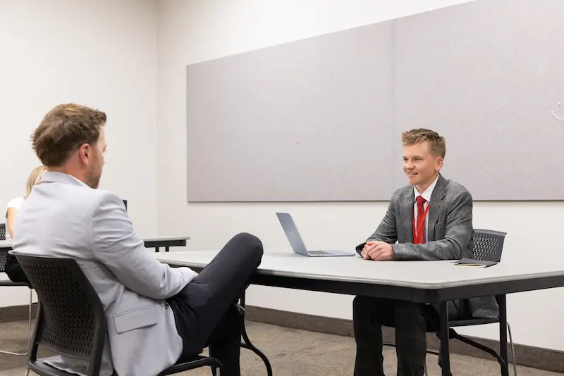 A man presenting to another man across a table 4 9