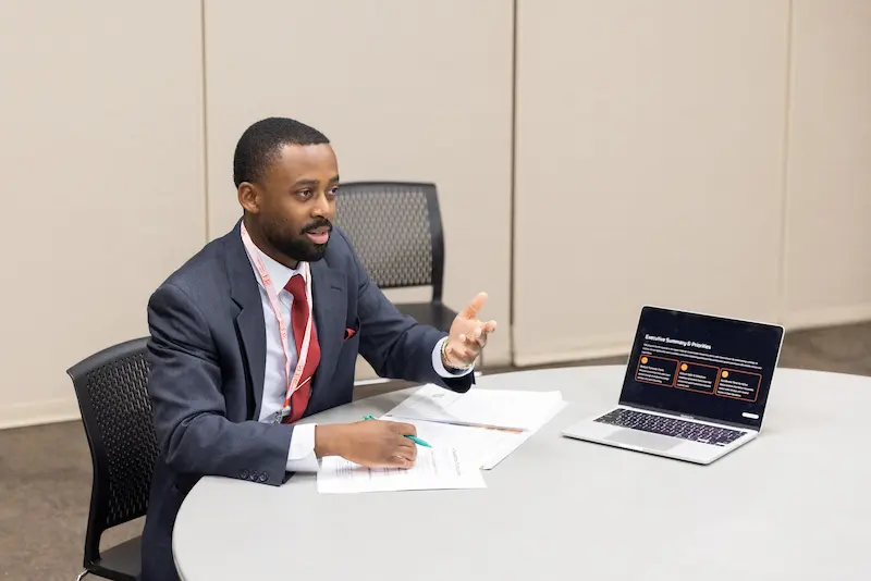 A man presenting at a table 2 10