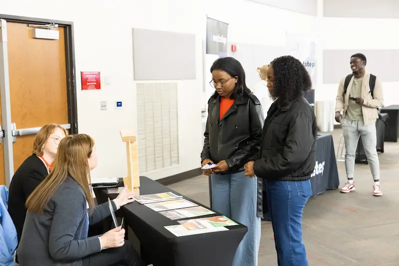 Four attendees discussing at a booth 27