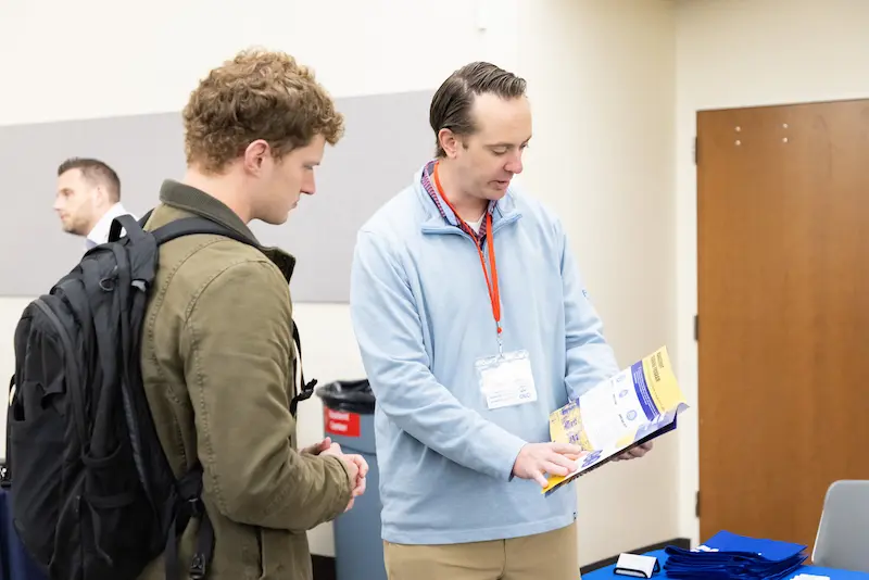 A man showing another man a pamphlet 28