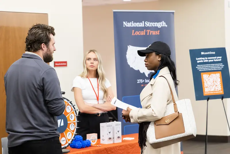 Three attendees discussing at a booth 32