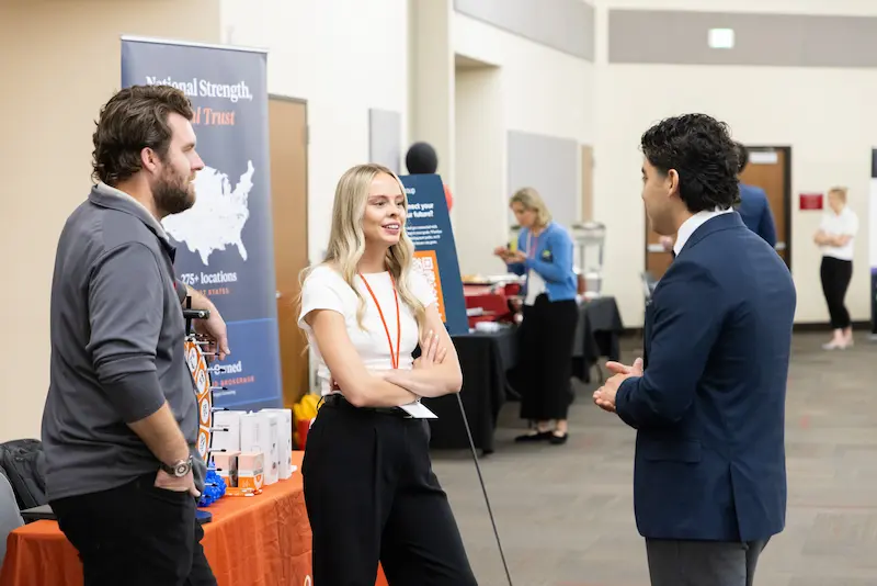 Three attendees discussing at a booth 2 34