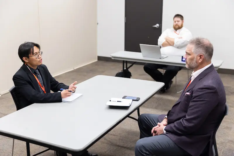 A man presenting to another man across a table 5 36