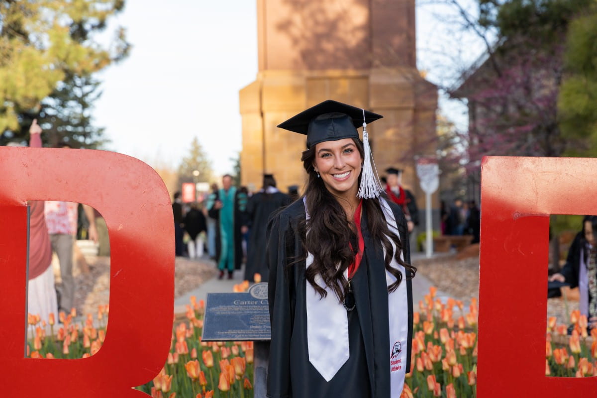 female SUU graduate in front of the Carter Carillon on campus