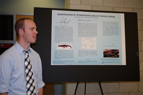 A male student with a research poster about Taricha granulosa