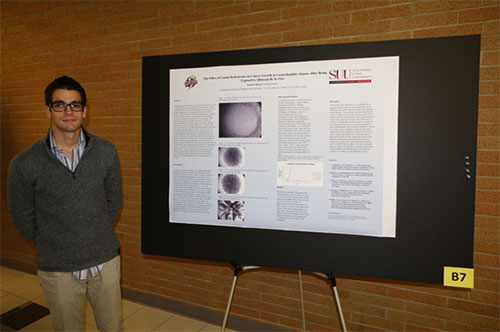 A man standing next to a large research poster