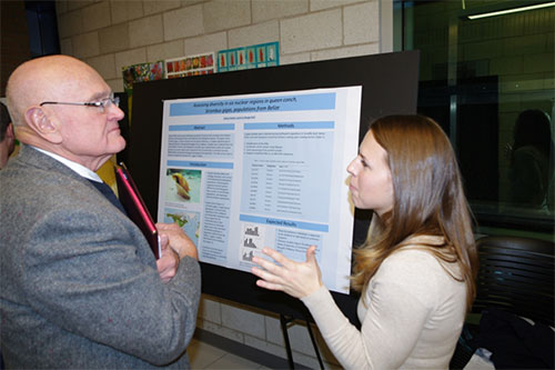 Female student presenting her research poster to Robert Eves