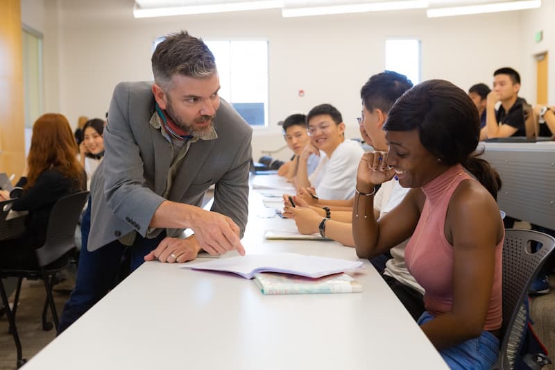 APPEL teacher speaking to a student and pointing to an open notebook on the table