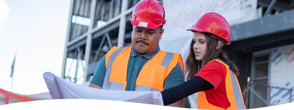 two people on a construction site looking at blueprints