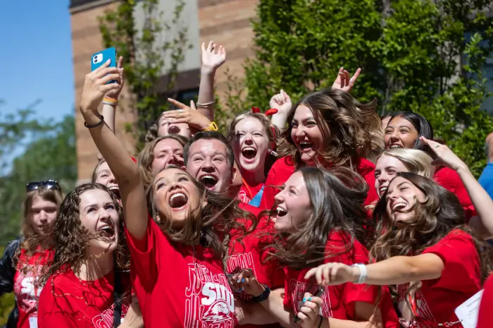 Photo of several happy SUU students taking selfies on campus