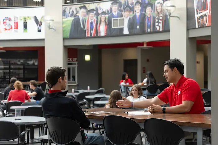 A student sitting with an SUU employee in the student center