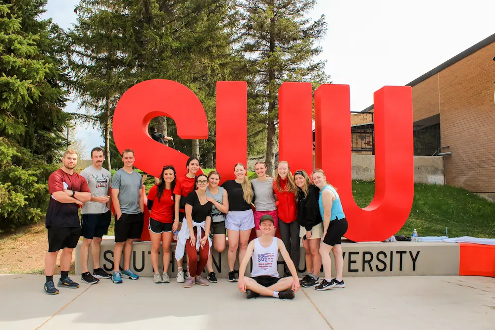 Runners in front of the SUU sign