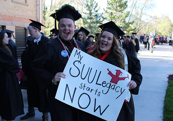 SUU Graduates holding a "My SUU Legacy starts now" Poster