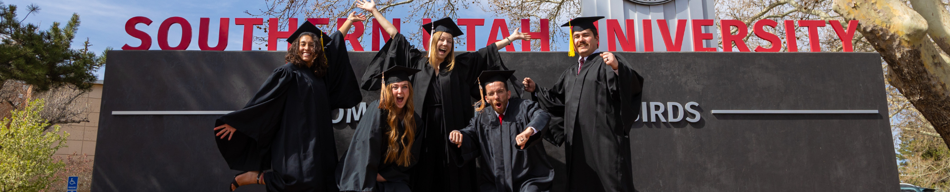 graduate student in cap and gown giving a thumbs up.
