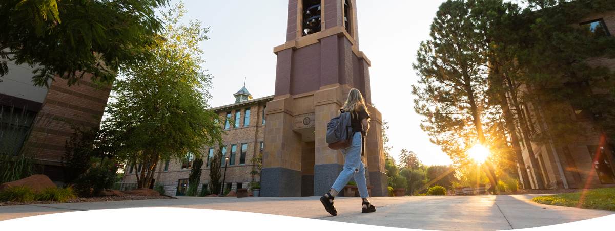 An image of a woman walking passed the bell tower on SUU campus